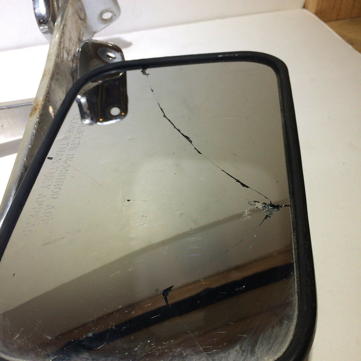 Close-up view of a cracked mirror from the Pickup Truck Set of Side Manual Mirrors with Chrome & Metal Housing, highlighting wear and tear.