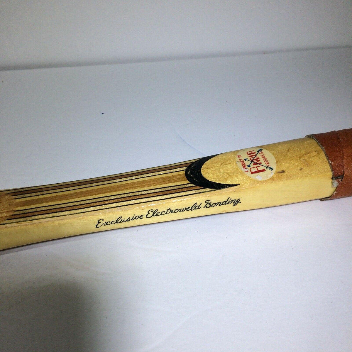 Close-up view of the grip of a Vintage Tournament Wood Tennis Racket Ash Frame 9 Ply Andia, showcasing exclusive electro welded bonding details on the handle.