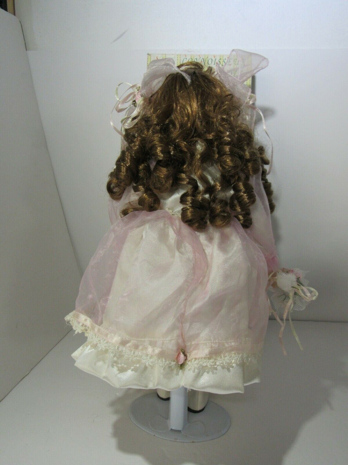 Back view of SEYMOUR MANN 'SALLY' Connoisseur Collection doll in a pink dress, highlighting the doll's elaborate hairstyle and clothing.