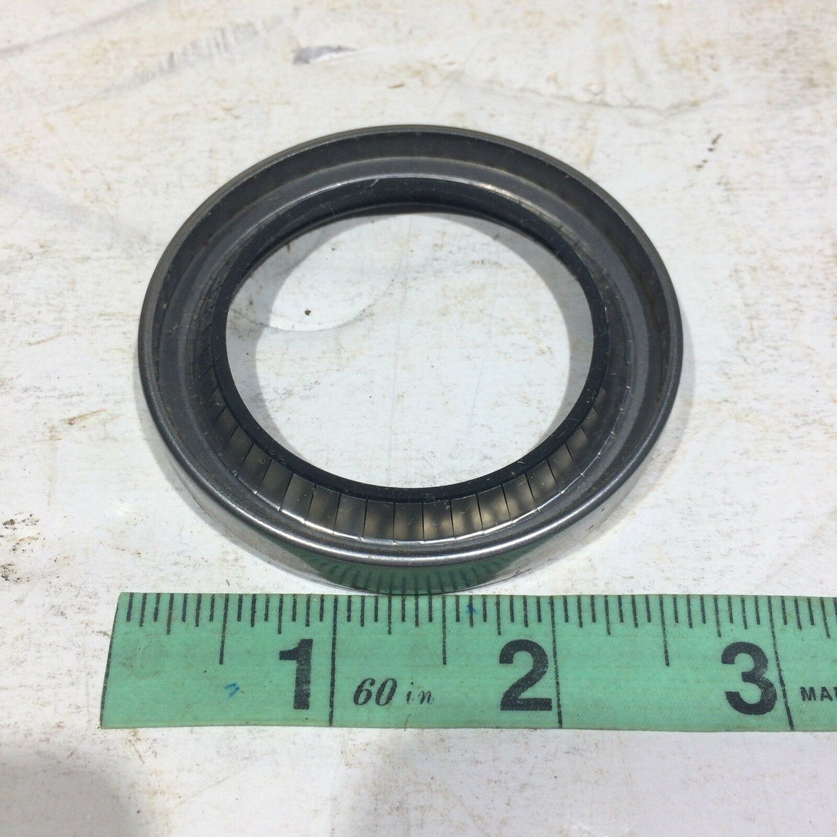 Garlock KLOZURE 63X1189 21158-1189 Oil Seal on a measuring scale, illustrating its size and high-quality construction for long-lasting performance in demanding environments.