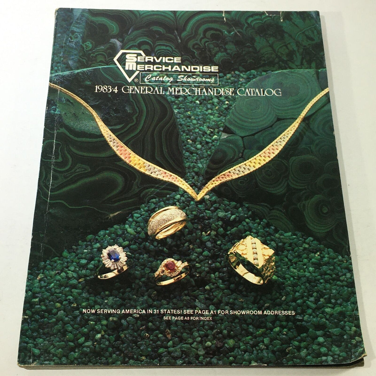 Cover of the VTG Service Merchandise Catalog Showroom 1983-1984 Volume 14 featuring jewelry designs, including rings and necklaces, set against a green stone background, highlighting vintage merchandise.