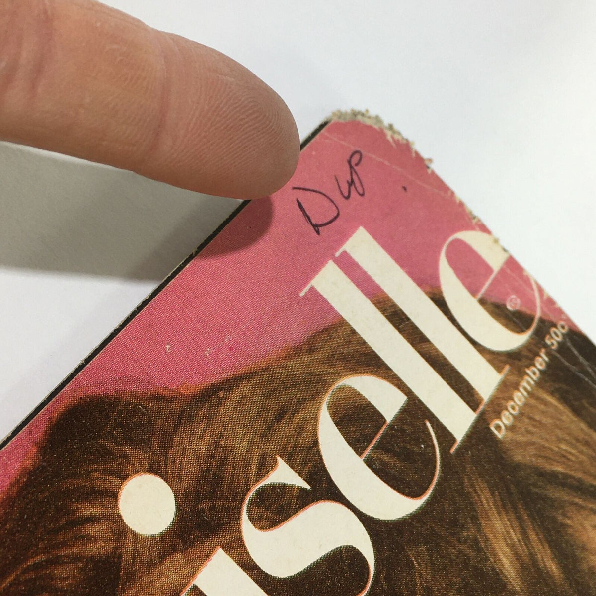 Detail of the top of the vintage Mademoiselle Magazine from December 1967, displaying handwritten notes and edge wear, with a finger indicating the notation on the cover.