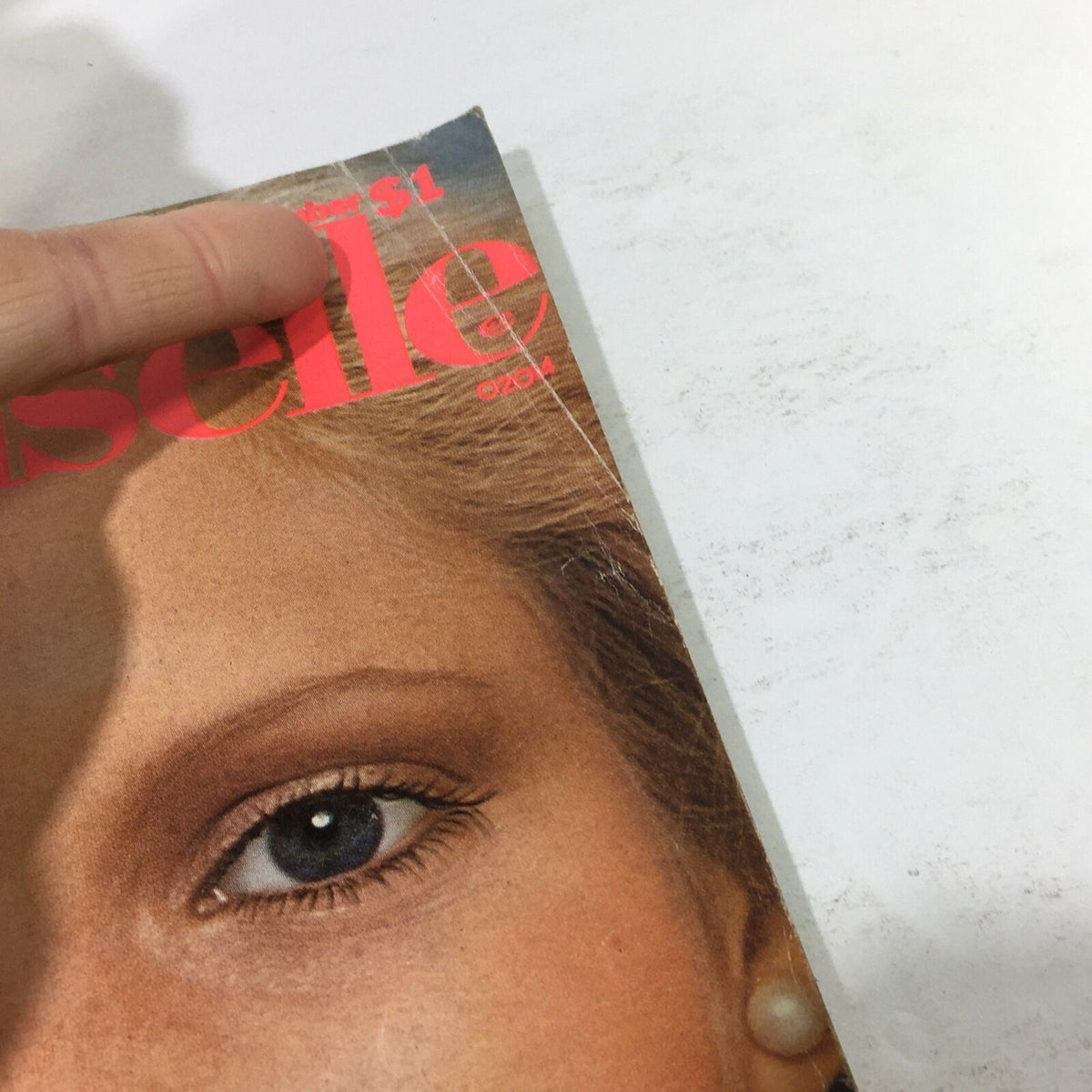 Close-up of the cover of Mademoiselle Magazine December 1975 showing Lisa Cooper's eye and a portion of the title. The image captures details like wear and texture representative of a vintage publication.
