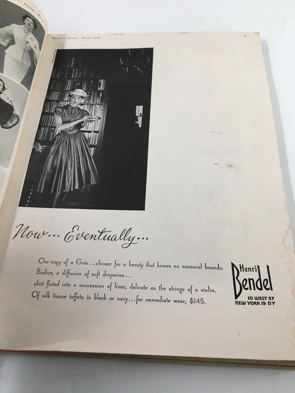 Interior page of Harper's Bazaar March 1952 displaying a model wearing a Grés dress amidst a library setting.