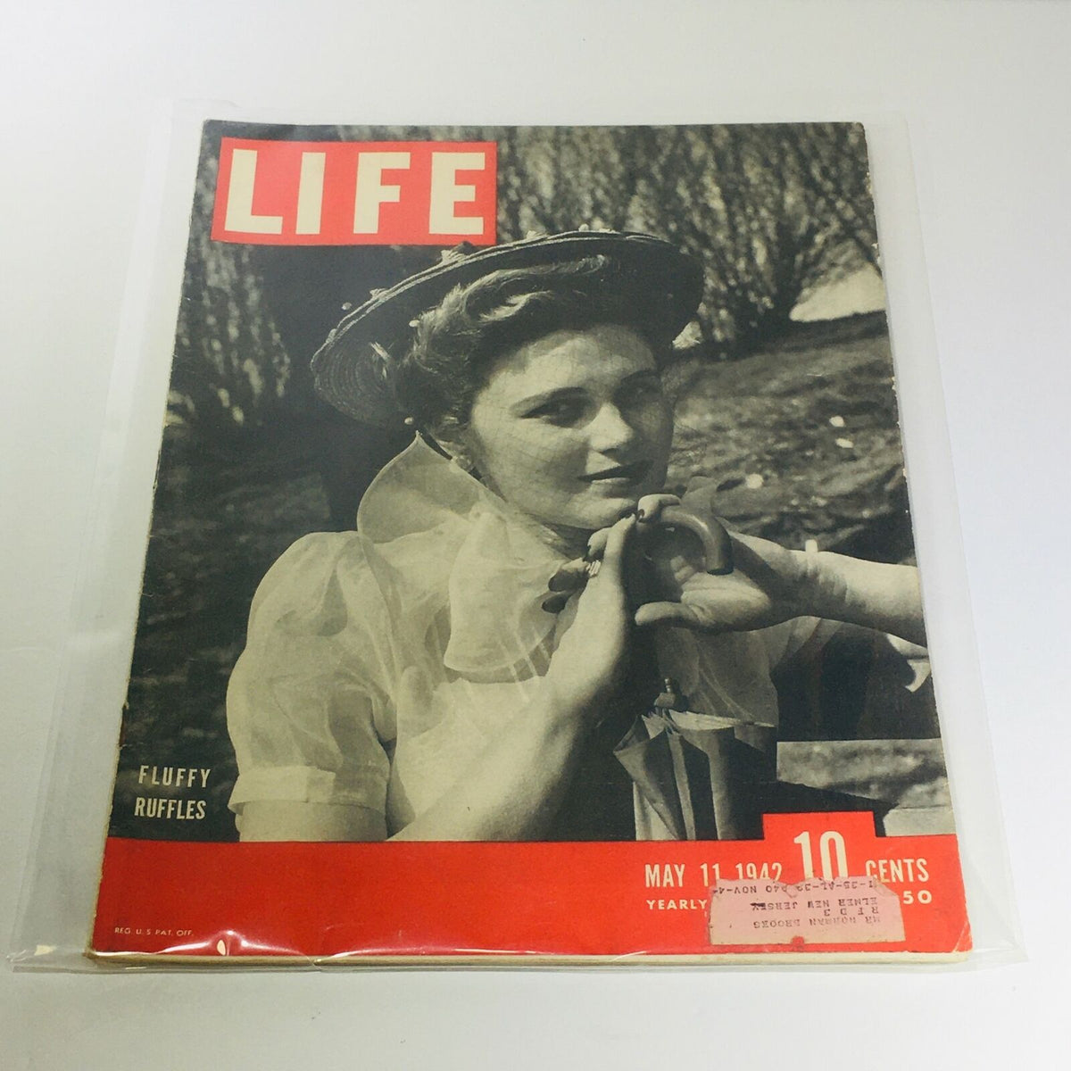 Vintage Life Magazine cover for May 11, 1942, themed 'Fluffy Ruffles', showcasing a woman in a vintage outfit with a hat, capturing the elegance of the era.