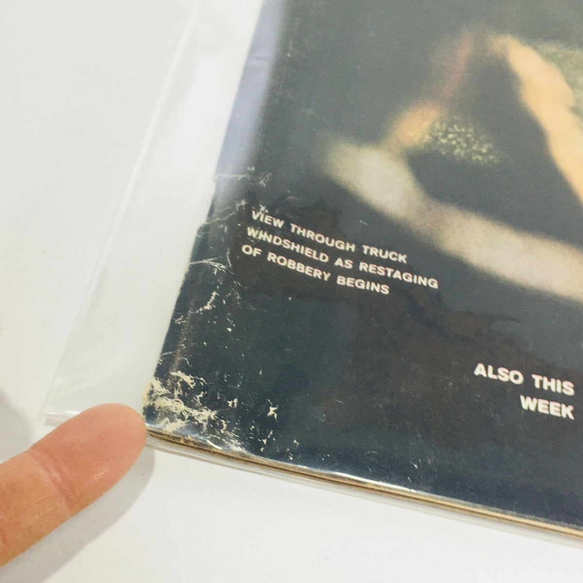 Close-up view of the bottom edge of the VTG Life Magazine: Aug 31 1962 cover showing signs of wear and featuring text related to the robbery reenactment.