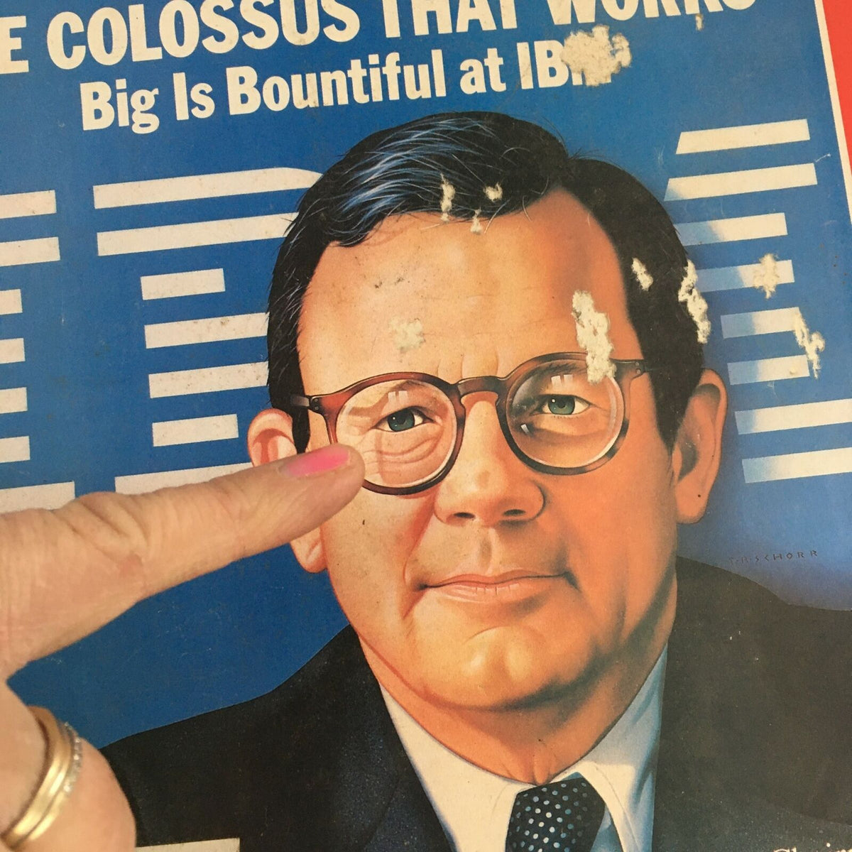 Detailed view of Chairman John Opel's portrait on the Time Magazine cover dated July 11, 1983, focusing on his glasses and expression, with signs of age on the magazine.