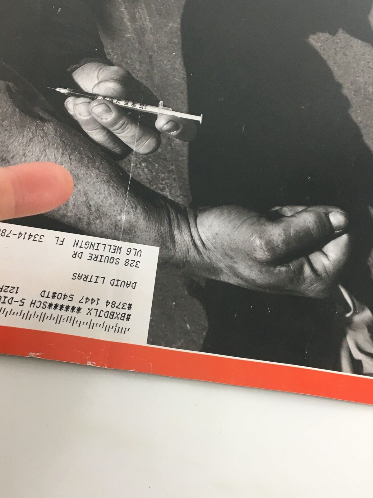 A close-up image highlighting a hand holding a syringe, part of the Time Magazine March 5, 2018 issue, 'The Opioid Diaries' photographed by James Nachtwey, depicting the reality of the opioid crisis.