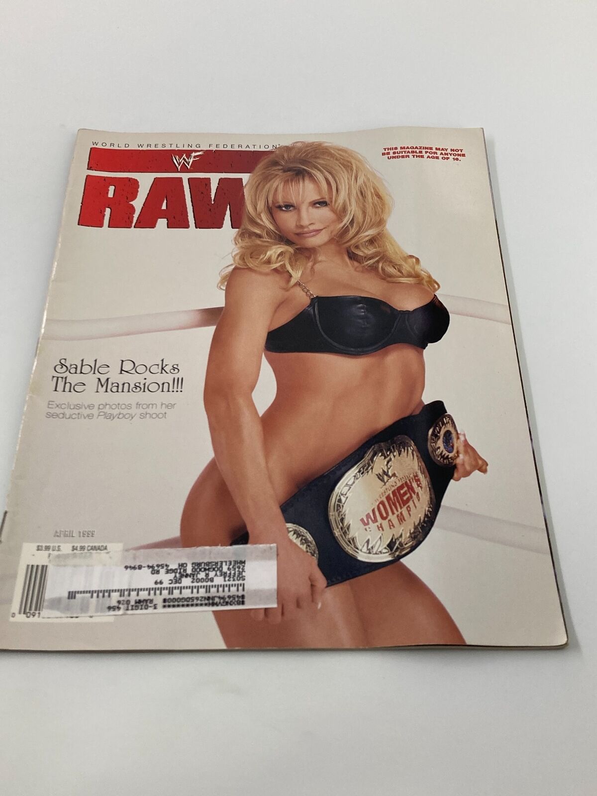 WWF Raw Magazine April 1999 featuring Sable on the cover in a black bra holding a women’s championship belt, showcasing her allure and connection to wrestling history.