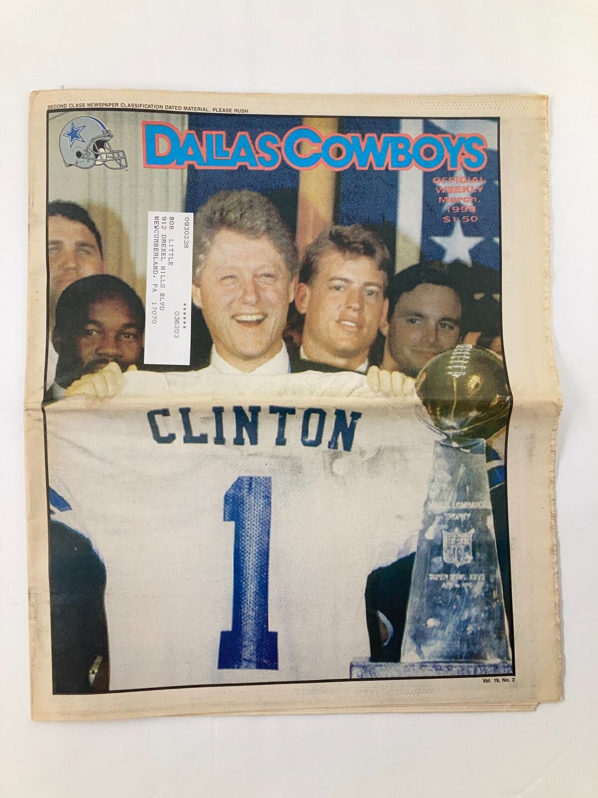 Cover of Dallas Cowboys Weekly Newspaper March 1993 Vol 19 #2 featuring Bill Clinton holding a jersey with the number 1, celebrating with the Super Bowl trophy.