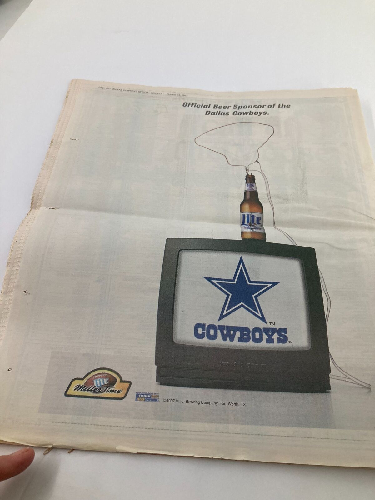 Advertisement from the Dallas Cowboys Weekly Newspaper dated October 18, 1997, showcasing the official beer sponsor with a television displaying the Dallas Cowboys star logo.