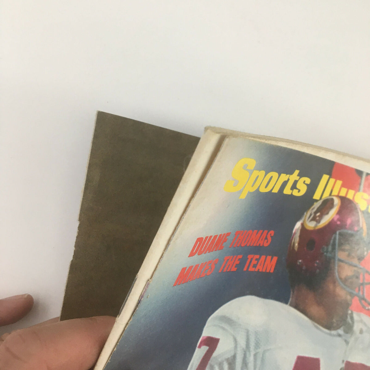 Side view of Sports Illustrated Magazine August 27, 1973, displaying the cover with Duane Thomas and the title 'MAKES THE TEAM', emphasizing its collectible nature.