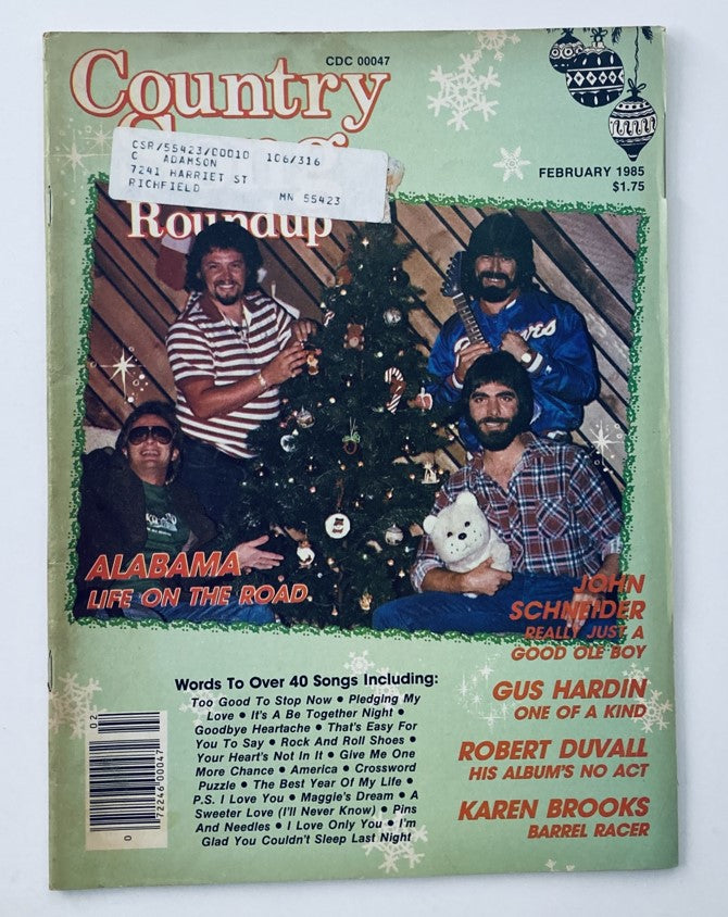 Cover of VTG Country Song Roundup Magazine from February 1985, featuring a festive Christmas-themed design with four men posing around a decorated tree, highlighting Alabama life on the road.