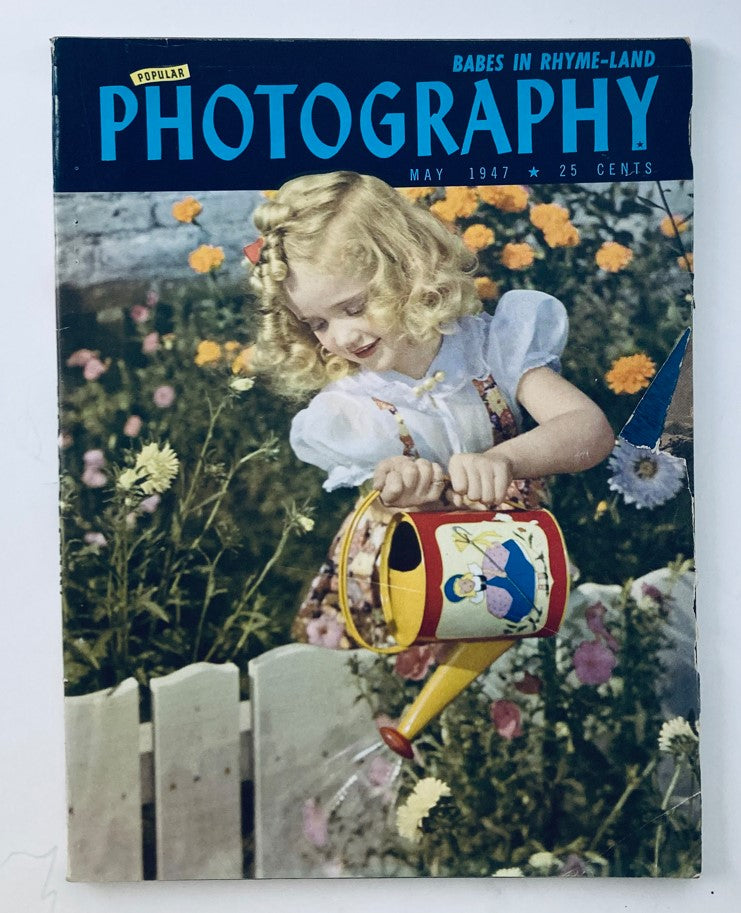 Cover of Popular Photography Magazine May 1947 Vol 20 No. 5 featuring a young girl watering flowers with a colorful watering can, illustrating the theme 'Babes in Rhyme-Land'.