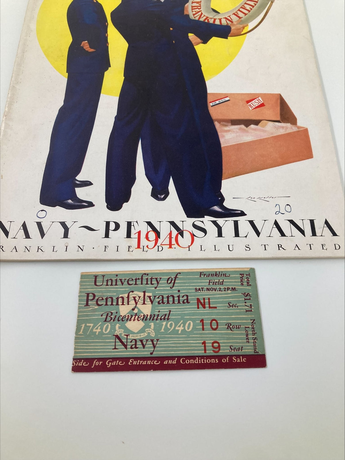 Close-up of the 1940 NCAA Football Navy vs Pennsylvania Official Statistics Program cover and the original ticket from the game, showcasing vintage design and colors.