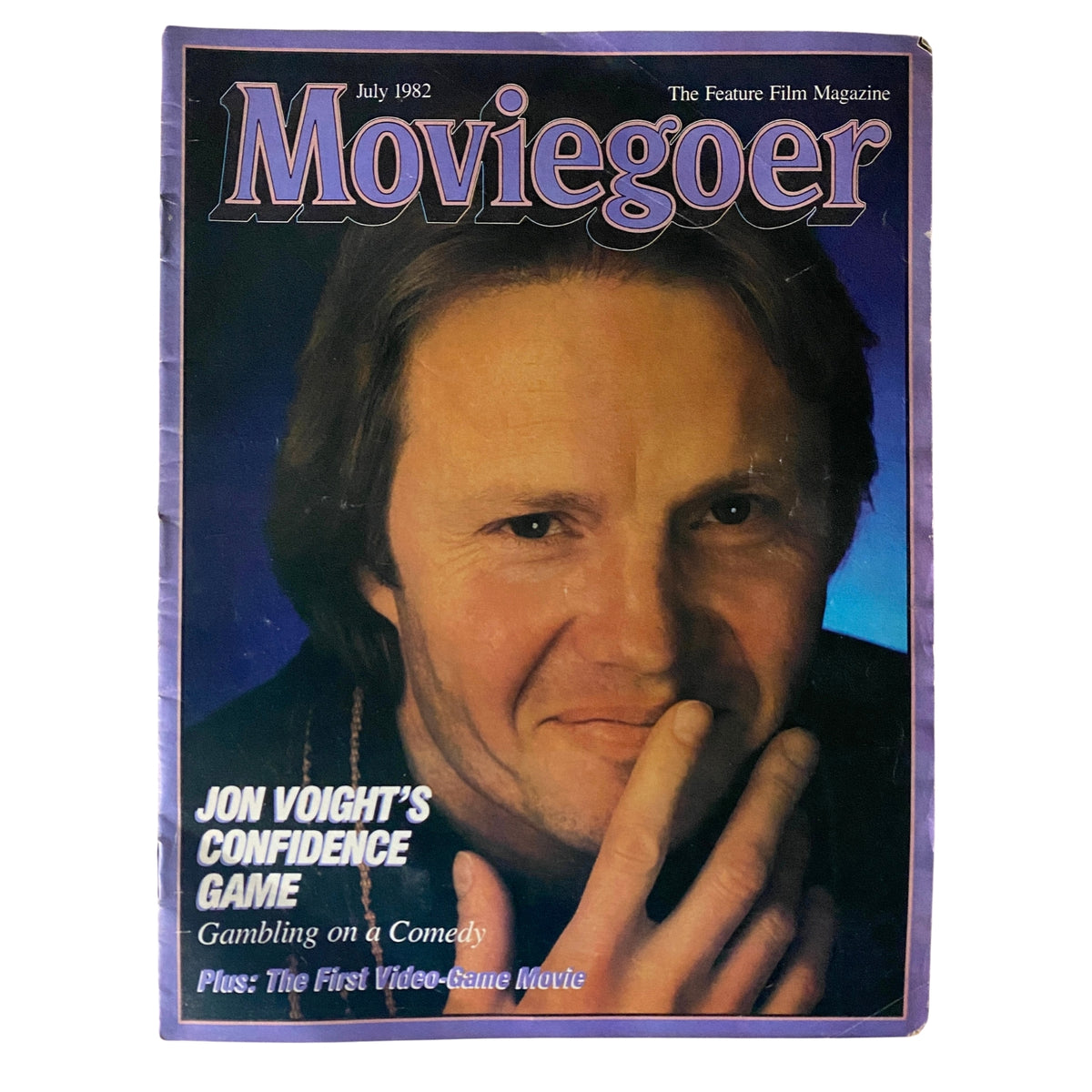 Cover of Moviegoer Magazine from July 1982 featuring Jon Voight, titled 'Jon Voight's Confidence Game'. The magazine discusses various films including the first video-game movie and highlights Voight's comedic role, capturing the essence of early 80s cinema.