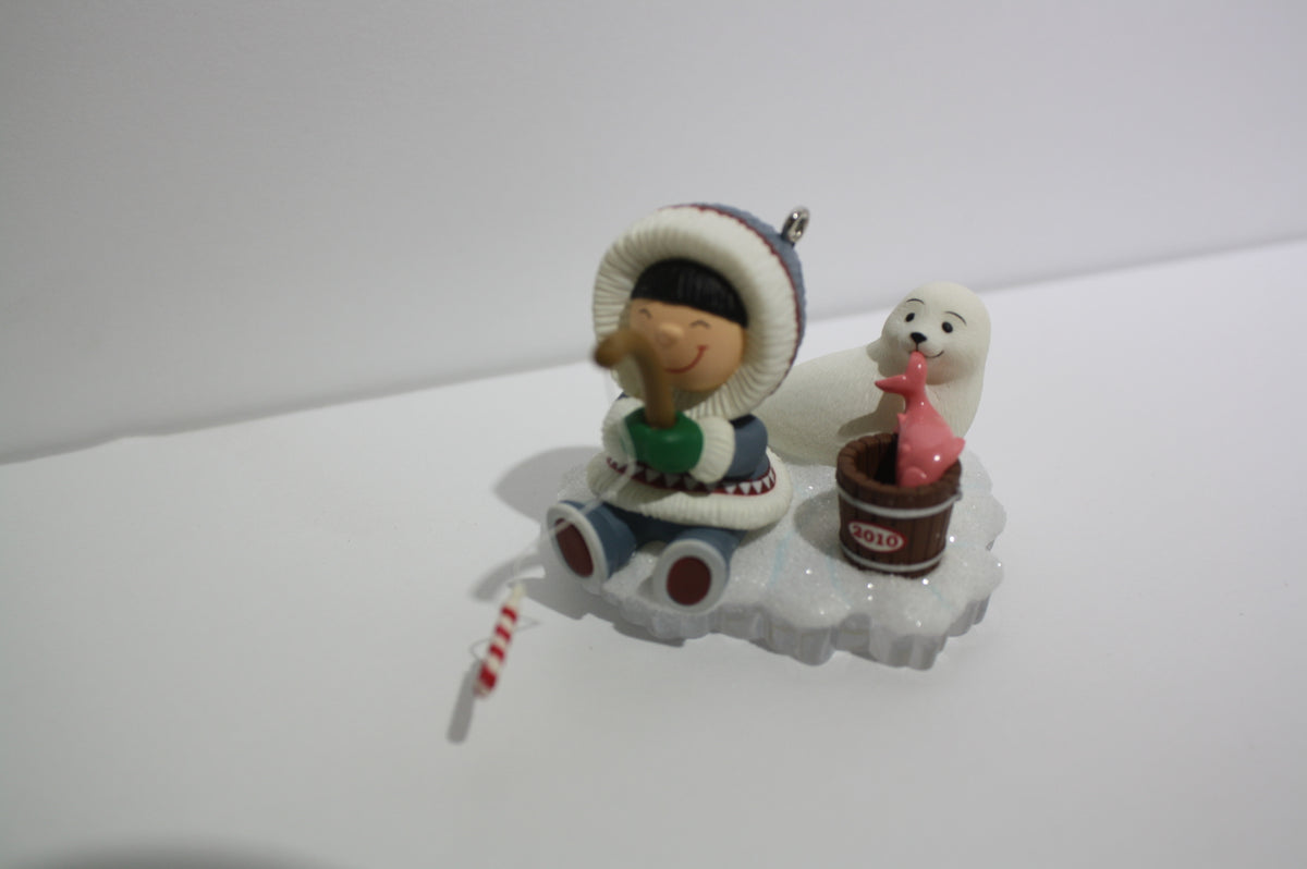 Close-up of 2010 Hallmark Keepsake Series Frosty Friends Fishing figurine, featuring a boy with a fishing rod and a seal with a pink fish.