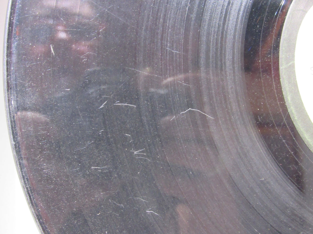 Close-up of The Beatles: Abbey Road vinyl record showing visible scratches and reflections, highlighting wear and tear for grading.