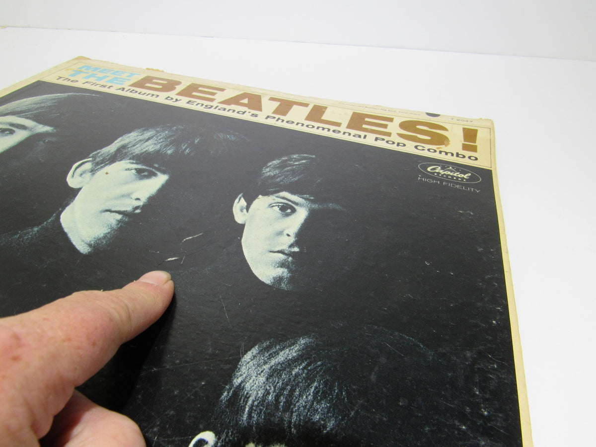 Detailed view of 'The Beatles: Meet The Beatles US Mono Capitol Records LP T 2047 Grade: G' cover highlighting the iconic band members with finger pointing at the artwork.