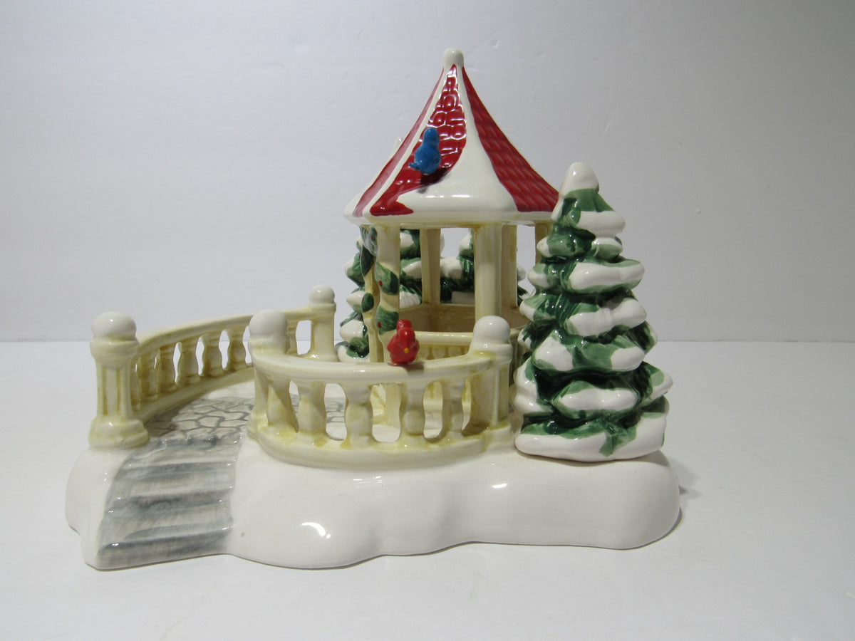 1989 Vintage Department 56 Snow Village Series Village Gazebo #5146-2, featuring a detailed gazebo with a red roof, surrounded by snowy evergreen trees and a pathway.