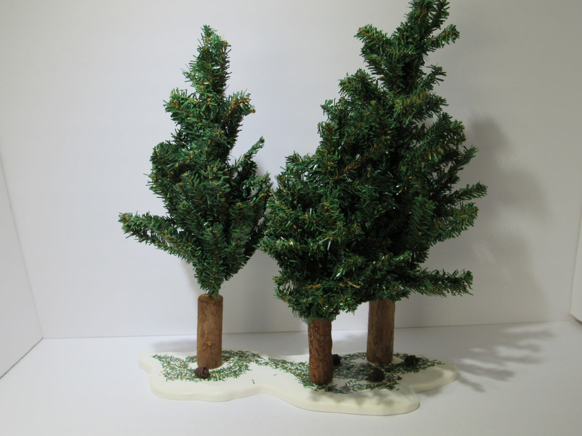 Vintage Department 56 Village Spruce Tree Forest with Wooden Base #5248-5 featuring three lush green trees with wooden trunks on a snow-covered base.