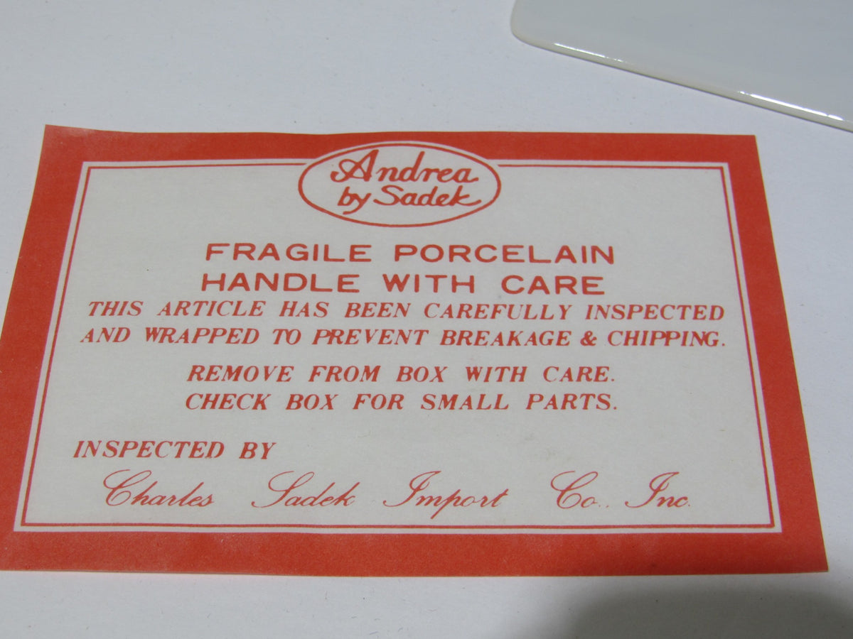Label for VTG Andrea by Sadek Porcelain Cake Plate and Server, indicating fragile porcelain handle with care, inspected for quality.