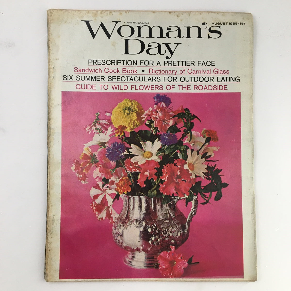 Cover of Woman's Day Magazine, August 1965, featuring a vibrant arrangement of wildflowers in a silver pitcher against a pink background with text highlighting 'Guide to Wild Flowers of the Roadside'.