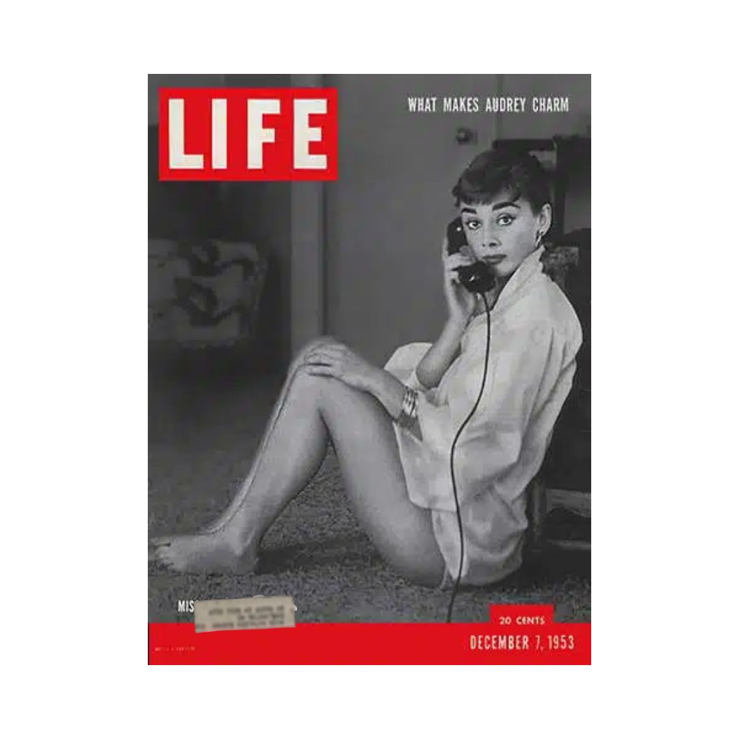 Cover of VTG Life Magazine dated December 7, 1953, featuring Audrey Hepburn, with the title 'What Makes Audrey Charm'. The image showcases Audrey sitting and holding a telephone, capturing her iconic style and charm.