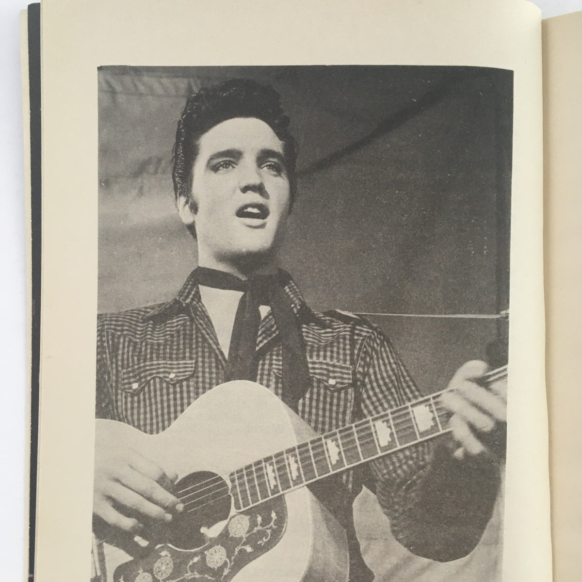 Interior page from 1973 Vintage Book Meet Elvis Presley by Favius Friedman, showcasing a black-and-white photograph of Elvis Presley singing while playing guitar.