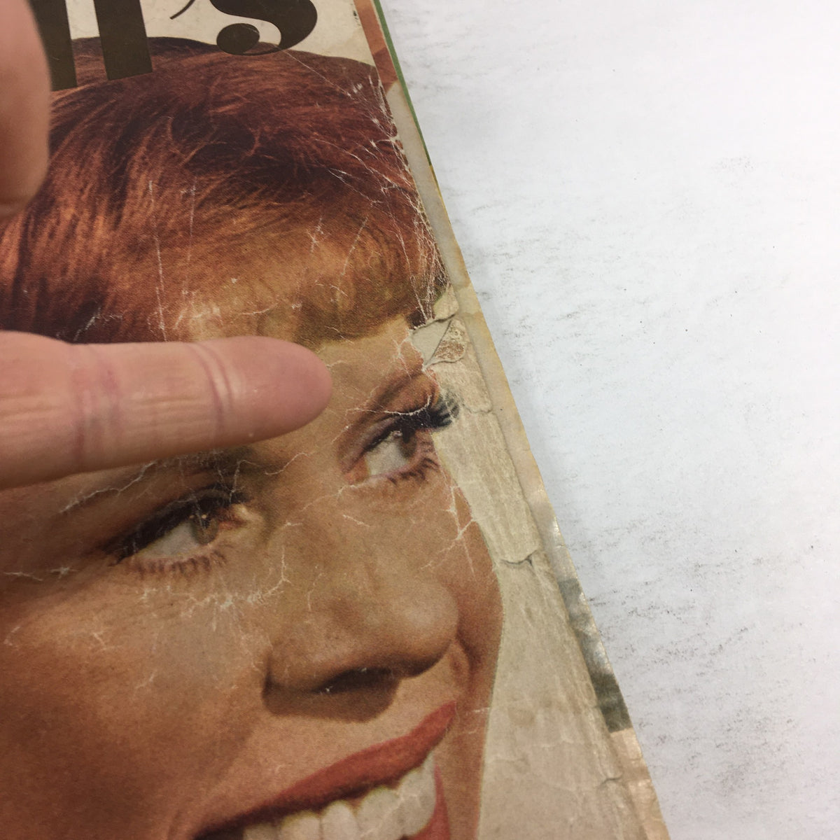 Detailed view of the worn front cover of the vintage McCall's Magazine from June 1976 featuring Carol Burnett, highlighting surface cracks.
