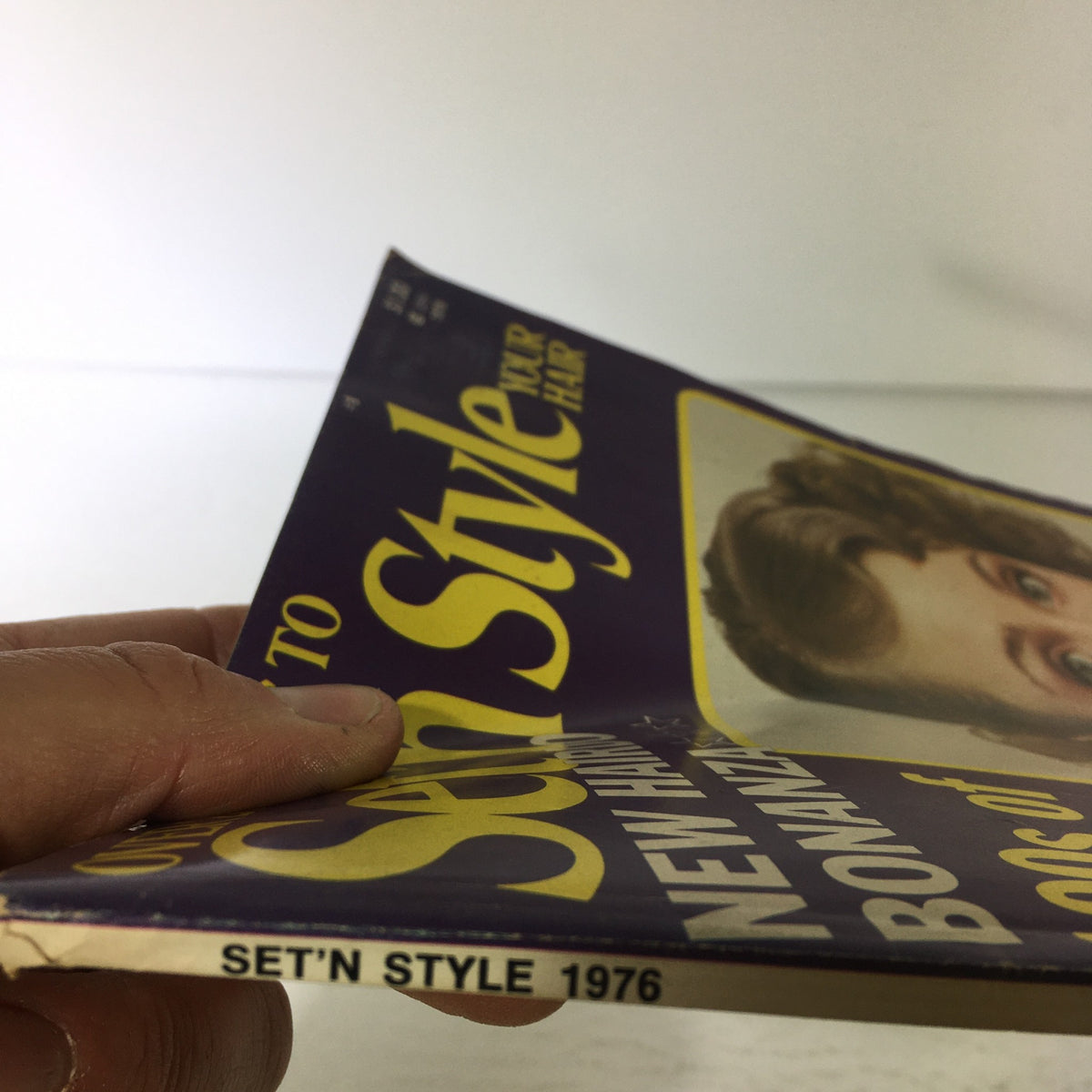 Side view of the VTG Set'N Style Magazine: 1976 highlighting the spine and details of the vintage publication on hairstyling options.