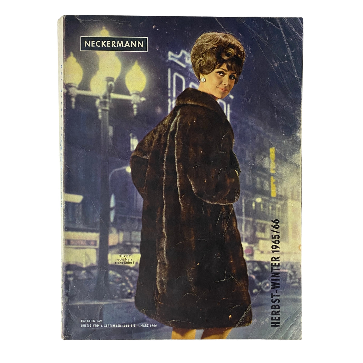 1965-1966 Neckermann Winter Catalog cover featuring a fashionably dressed woman in a fur coat, standing against a nighttime urban backdrop with streetlights.