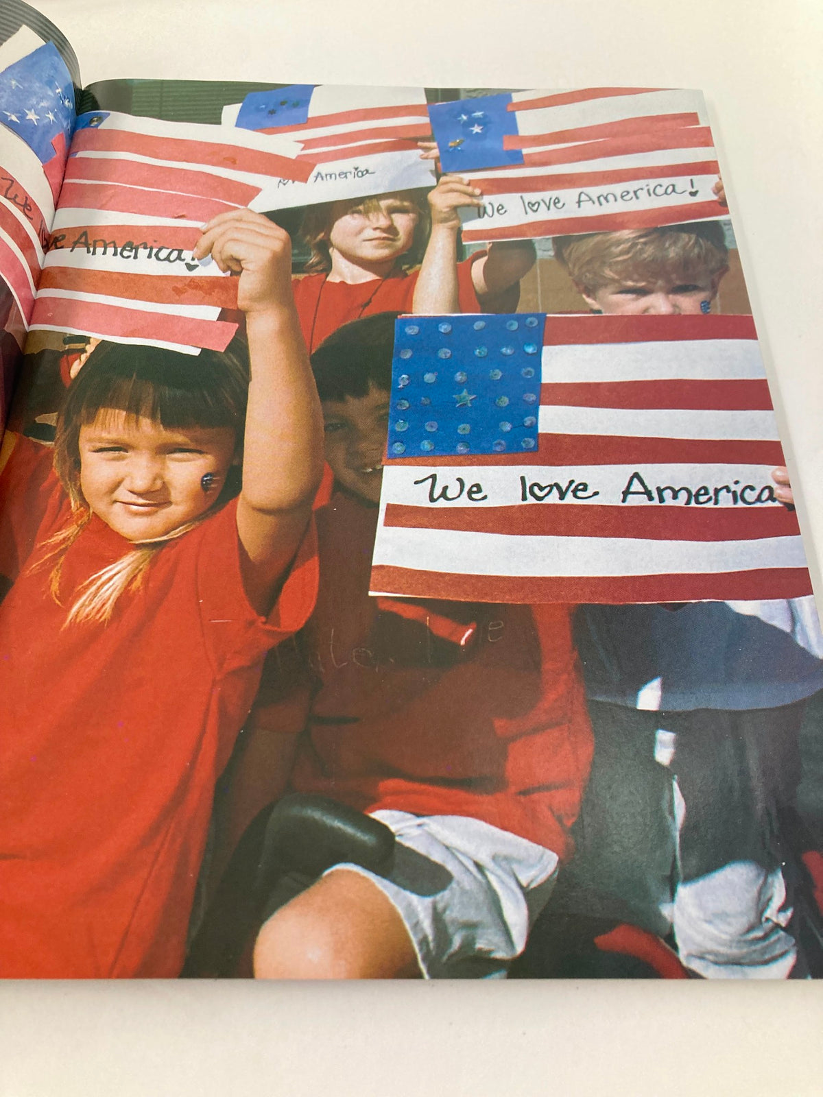 Inside page of Newsweek Magazine Fall 2001 The Spirit of America, depicting children holding American flags with the message 'We love America' in a show of unity.