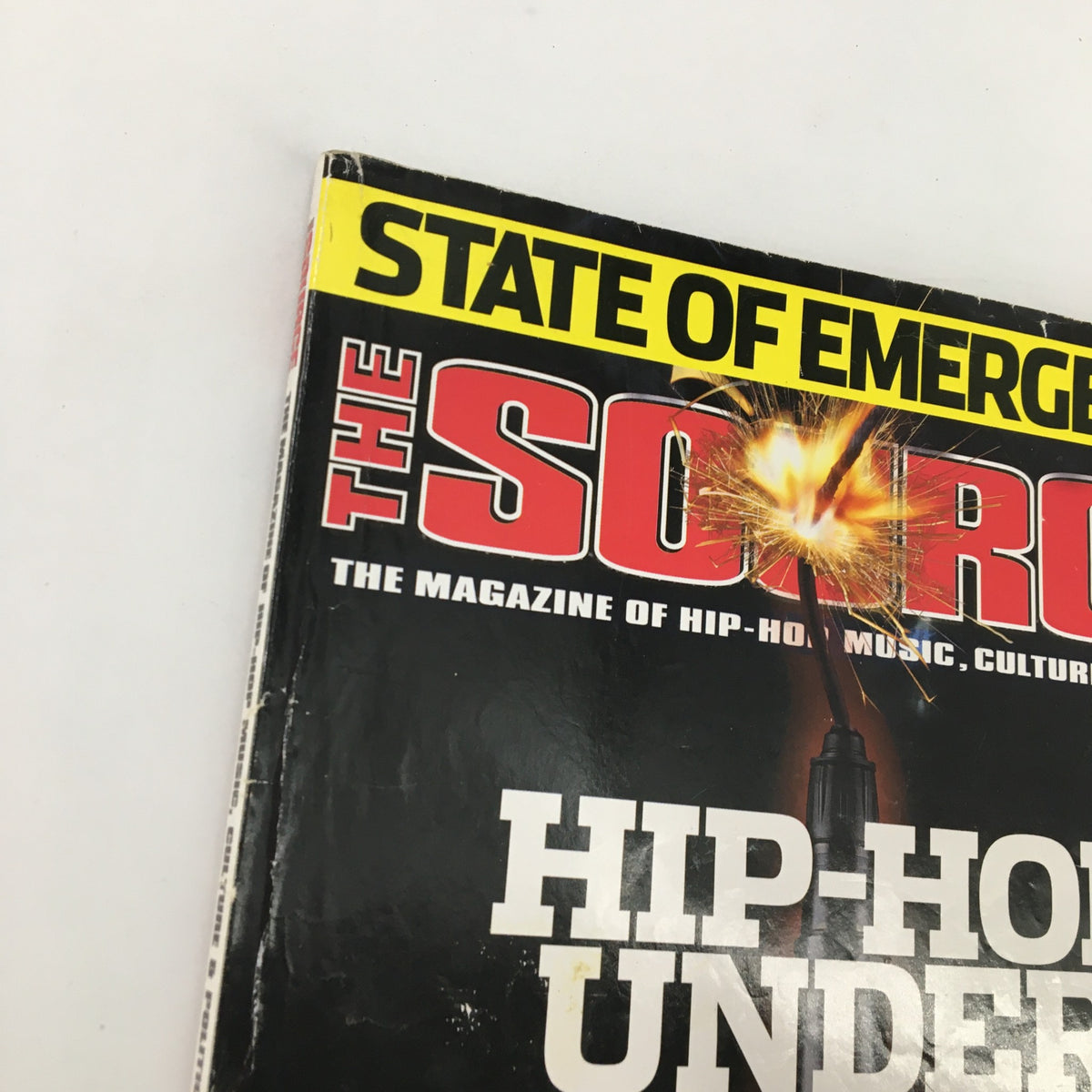 Top view of The Source Magazine March 2003 No. 162 displaying 'STATE OF EMERGENCY' and 'HIP-HOP UNDER ATTACK', highlighting the magazine's theme of addressing contemporary issues in the hip-hop culture.