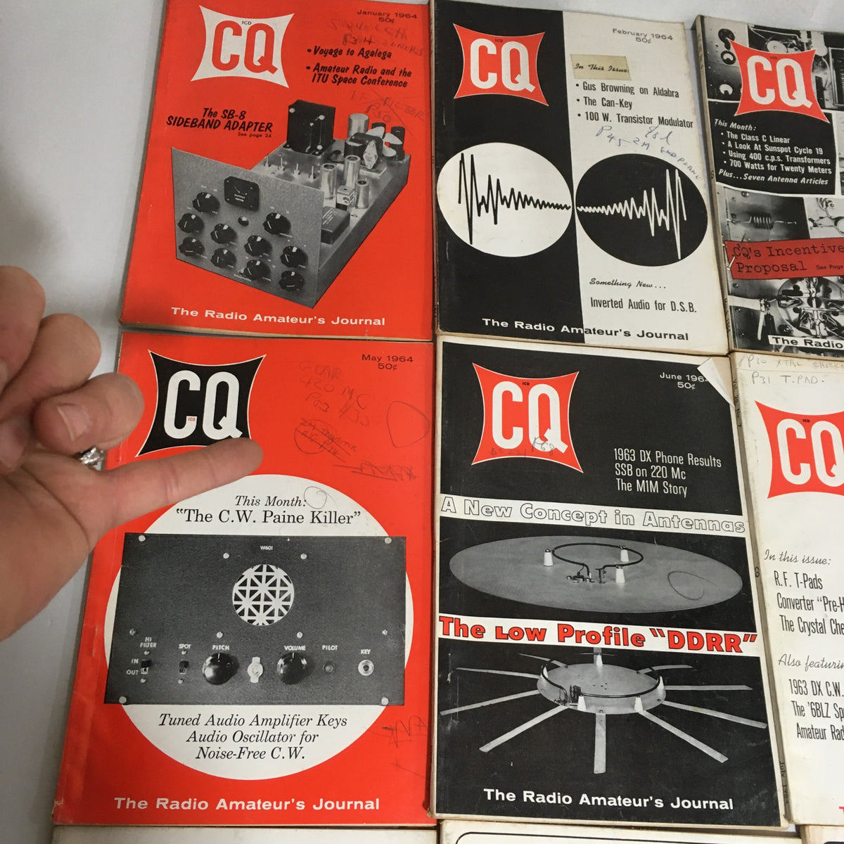 Close-up of multiple issues from the 1964 CQ The Radio Amateur's Journal collection, highlighting the covers with technical illustrations and topics relevant to amateur radio.