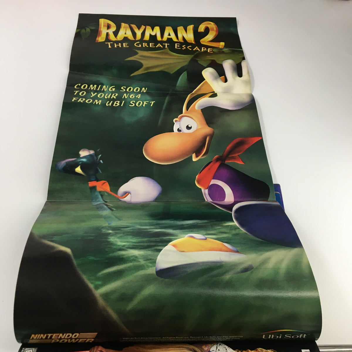 Poster included in Nintendo Power Magazine Vol. 118 March 1999 for Rayman 2: The Great Escape showcasing colorful artwork.