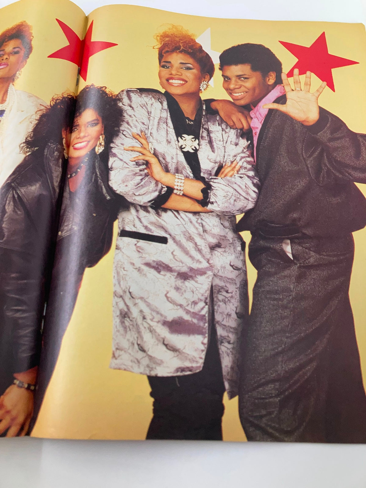 Another inner spread from the Vintage Lookin Magazine May 10 1986 Issue featuring four individuals in trendy attire with bright star graphics in the background, highlighting the magazine's pop culture content.