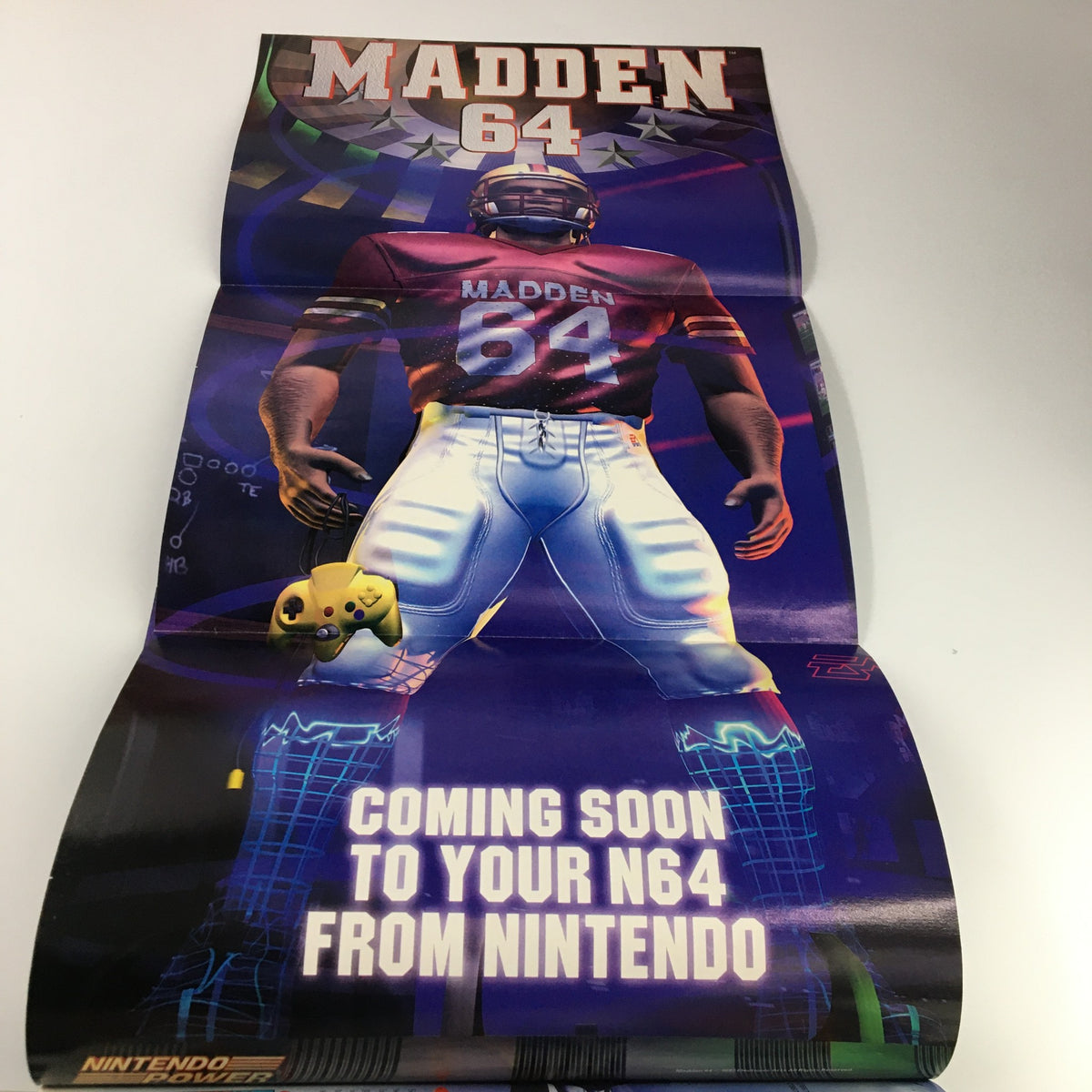 Fold-out poster from Nintendo Power Magazine #101 from October 1997, promoting 'Madden 64' game with an illustration of an athlete in a striking pose. A valuable addition for collectors.