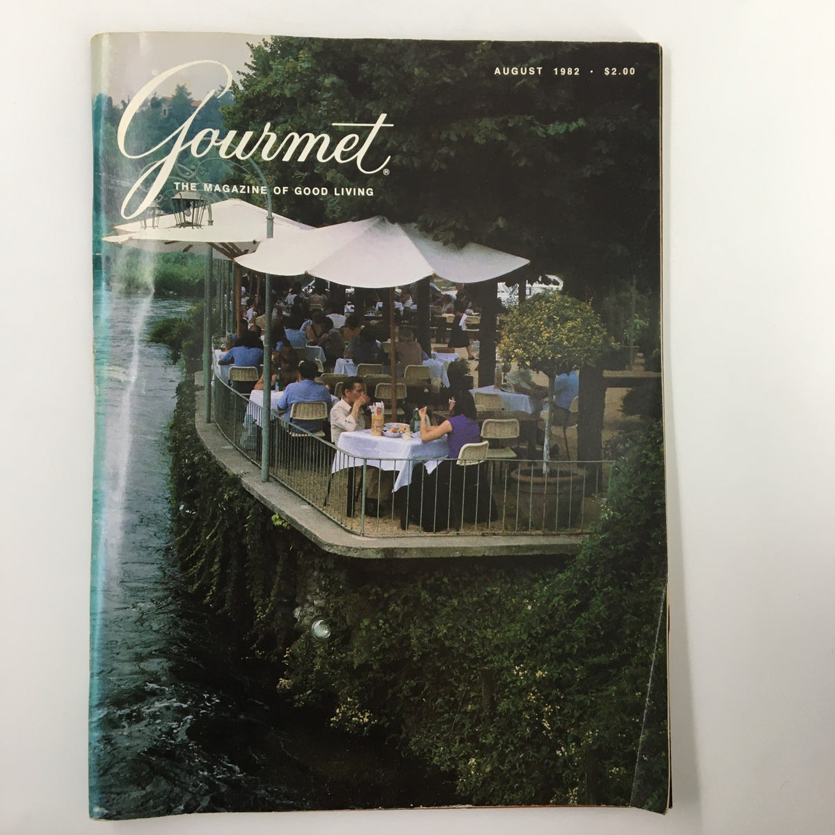Cover of VTG Gourmet Magazine August 1982 featuring an outdoor dining scene at Antica Locanda Mincio, showcasing guests enjoying meals under umbrellas by a scenic waterway.