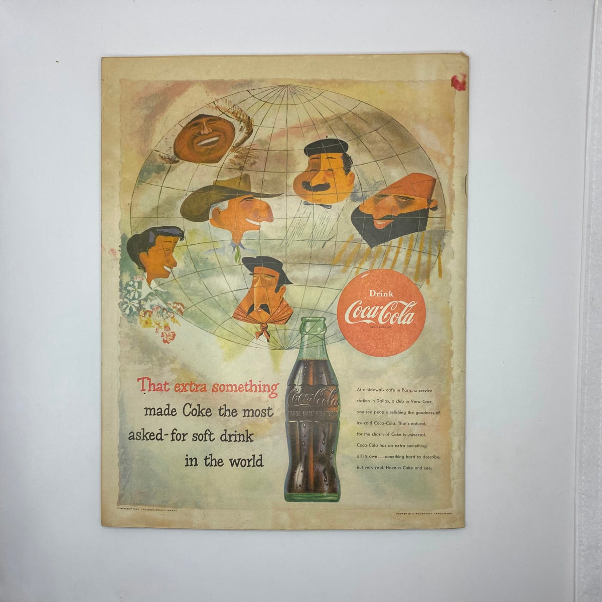 Vintage advertisement page from Boys' Life magazine May 1954, featuring a Coca-Cola ad with illustrations and text promoting Coke as the most asked-for soft drink in the world, accompanied by graphics of global faces and a bottle.