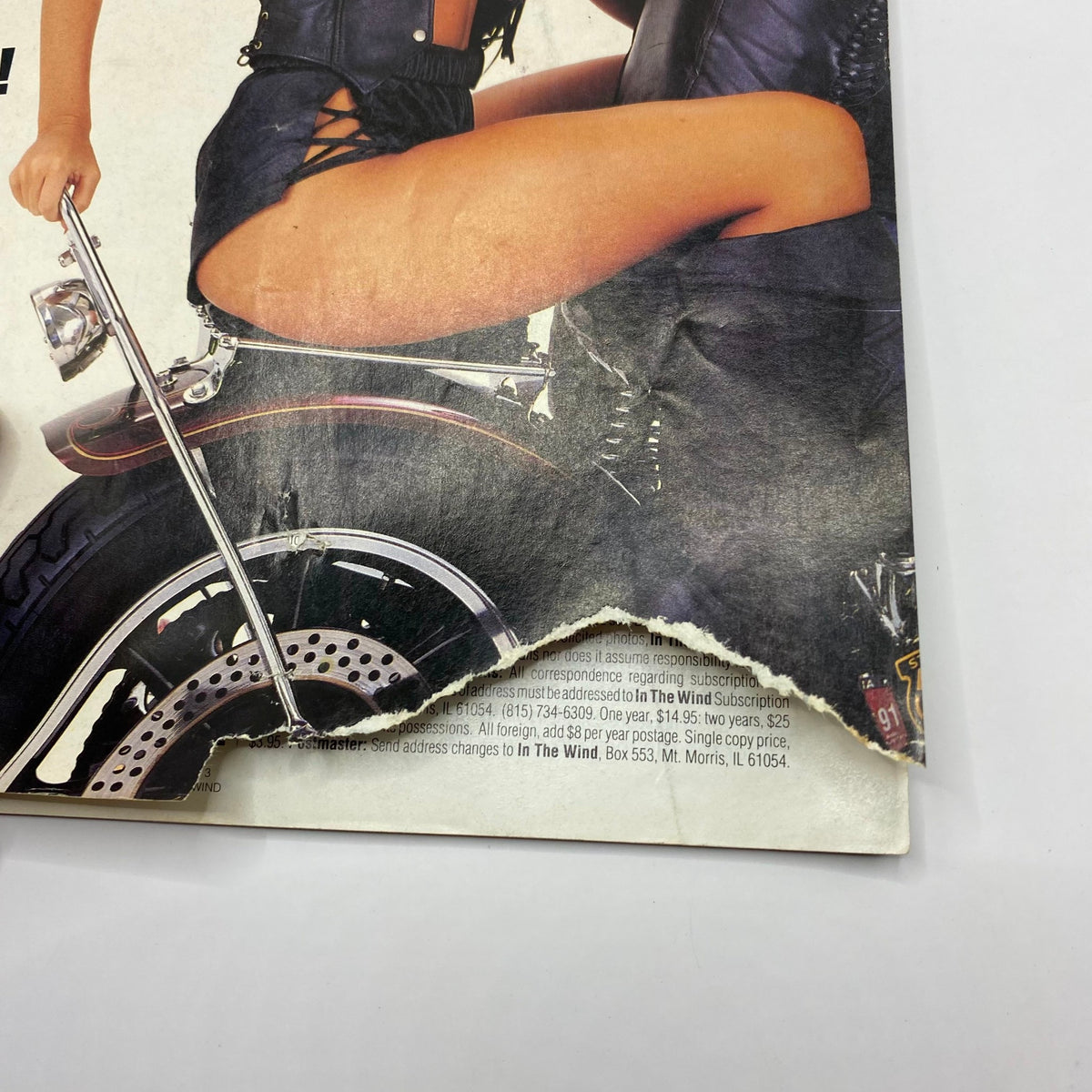 Close-up of the cover of 'In The Wind Magazine March 1992' showing wear at the edge, illustrating the magazine's vintage character and history within motorcycle enthusiasts' collectibles.