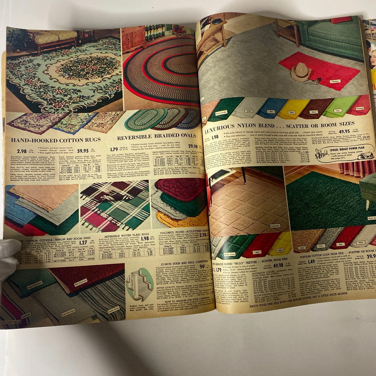Page from the 1955 Spiegel Fall and Winter Catalog displaying hand-hooked cotton rugs and braided oval rugs, reflecting vintage flooring styles and mid-century design.