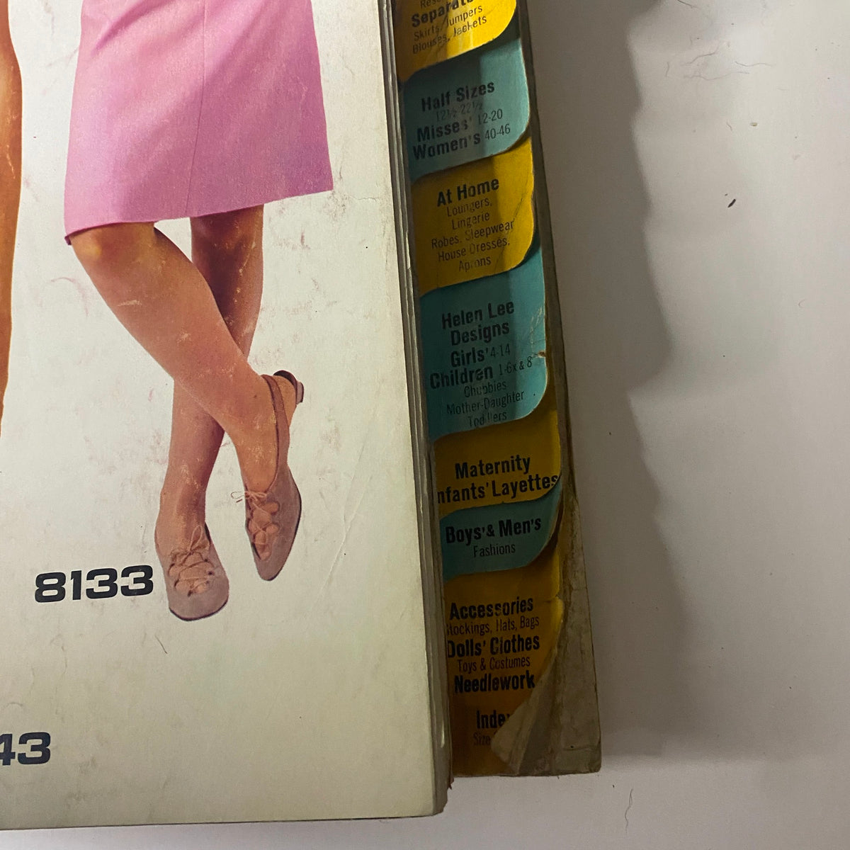 A close-up of the 1966 February McCall's Designers' Collection Catalog featuring a model wearing a pink dress, with sections indicating Half Sizes and the At Home clothing line.