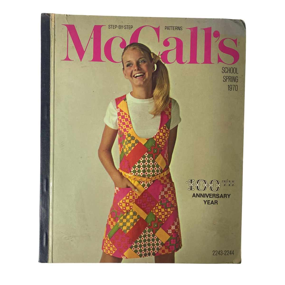 1970 McCall's School Spring Huge Store Retail Counter Catalog cover featuring a girl wearing a colorful fashion apron dress with a patchwork design, representing vibrant 1970s youth fashion.
