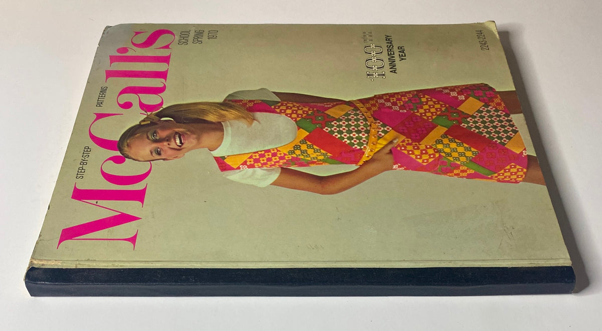 Side view of the 1970 McCall's School Spring Huge Store Retail Counter Catalog showcasing its cover with a smiling girl in a colorful patchwork dress, celebrating nostalgic fashion trends.
