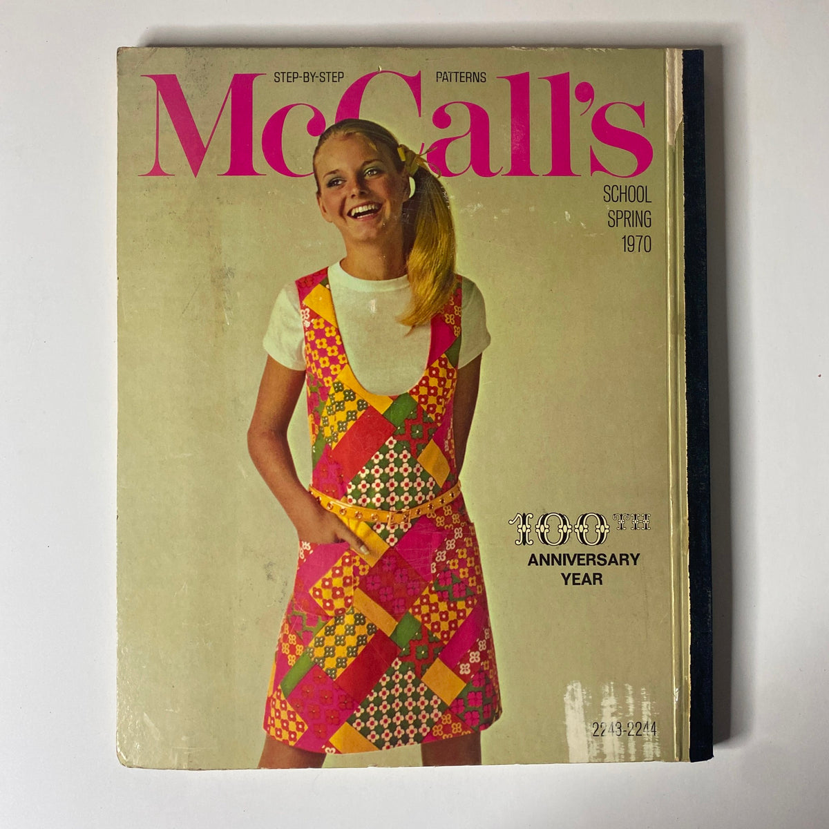 1970 McCall's School Spring Catalog cover with a cheerful young girl wearing a vibrant, patterned dress, celebrating the 100th anniversary of McCall's Patterns.