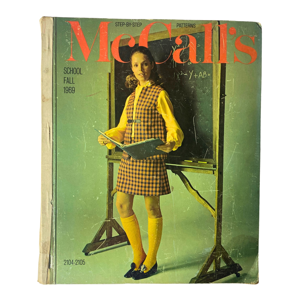 1969 McCall's School Fall Huge Store Retail Counter Catalog cover featuring a girl in a vintage plaid dress with knee-high socks, holding a book, standing in front of a chalkboard.