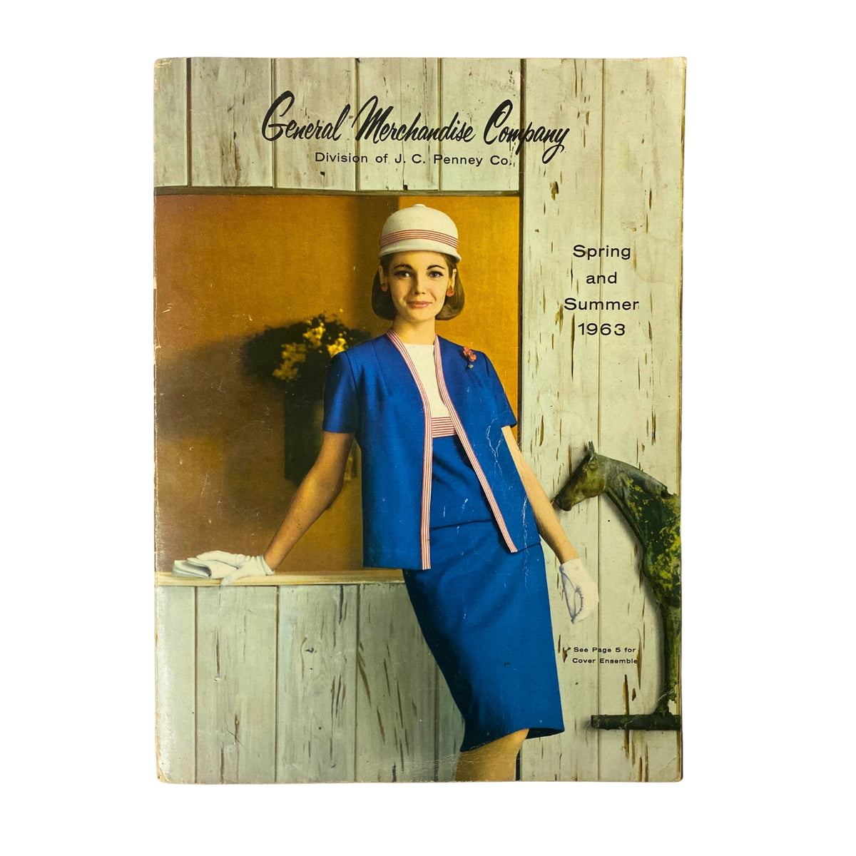 Cover of the 1963 General Merchandise Company Spring and Summer Catalog featuring a woman in vintage fashion. She wears a blue outfit with a matching hat against a rustic background.