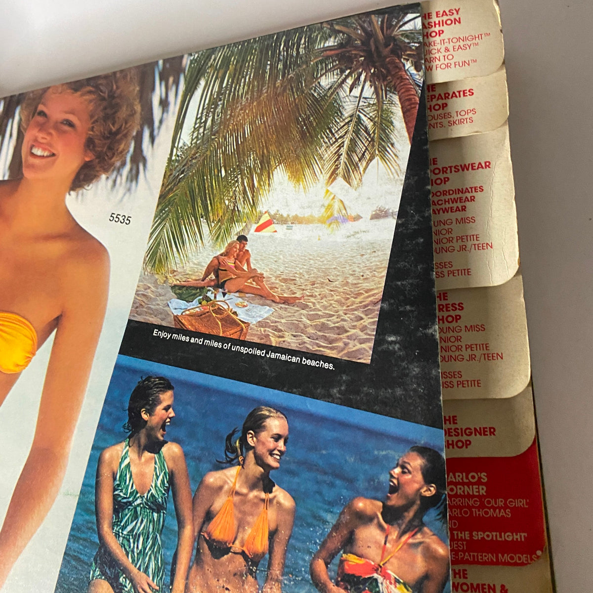 Inside layout of the 1977 July Carefree Patterns McCall's Summer Catalog, showcasing models in swimsuits and a tropical beach setting, emphasizing summer fashion trends.