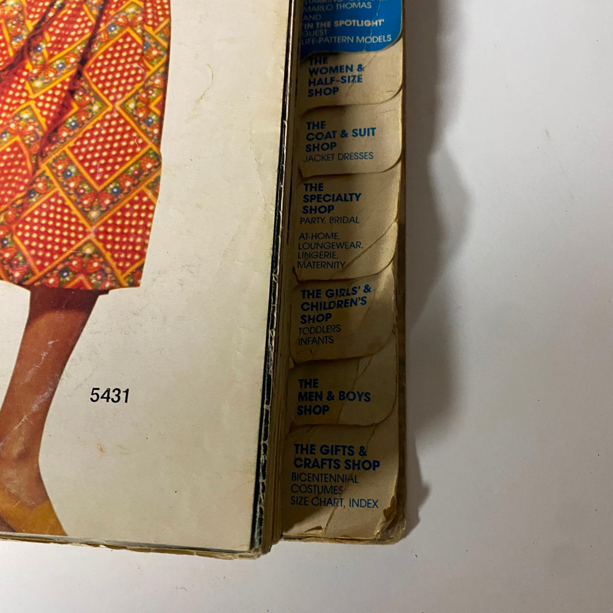 Cover of the 1970s March Carefree Patterns from McCall's Catalog featuring a stylish dress with bright patterns and a list of shops for various clothing styles.